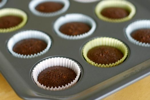 a muffin tin filled with chocolate cupcakes on top of a wooden table