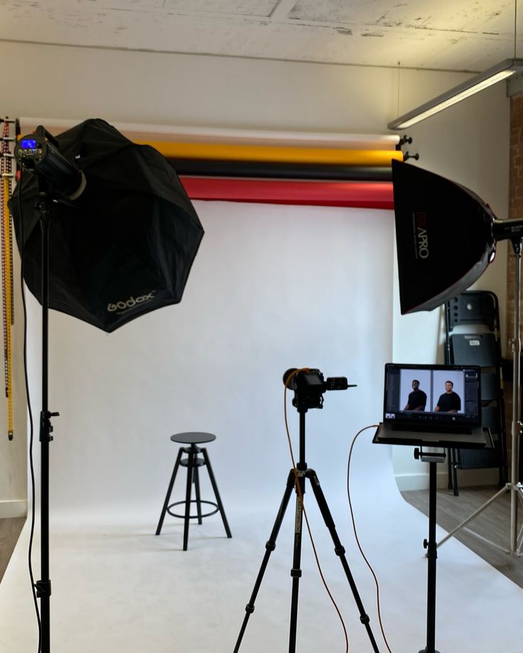 a camera and tripod set up in front of a white backdrop for a photo shoot