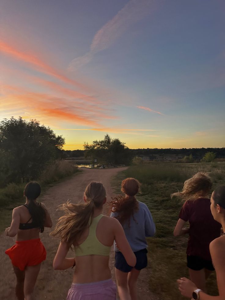 group of people running on dirt road at sunset