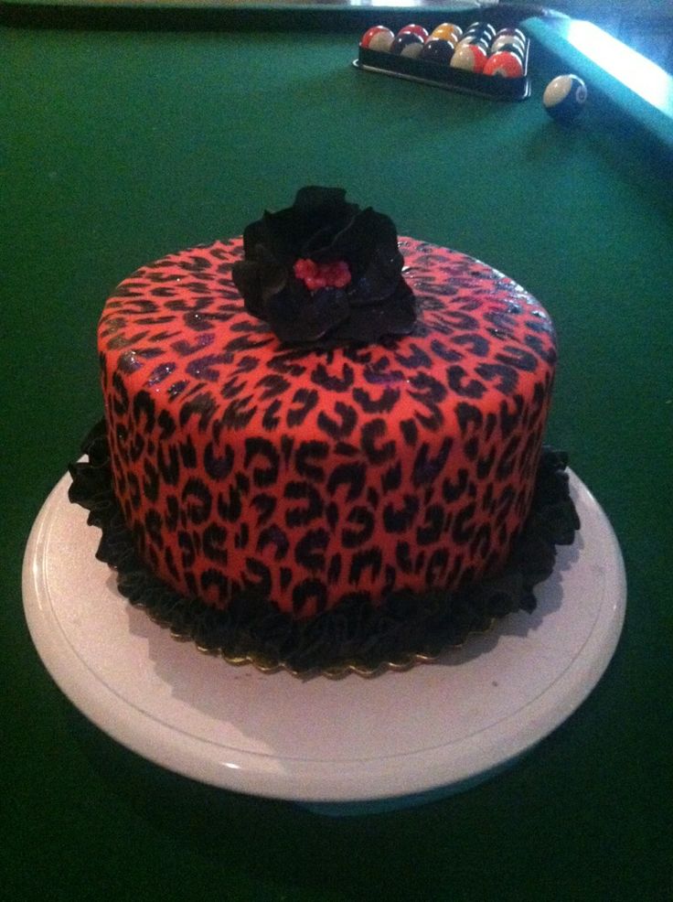 a decorated cake sitting on top of a white plate next to a pool ball table