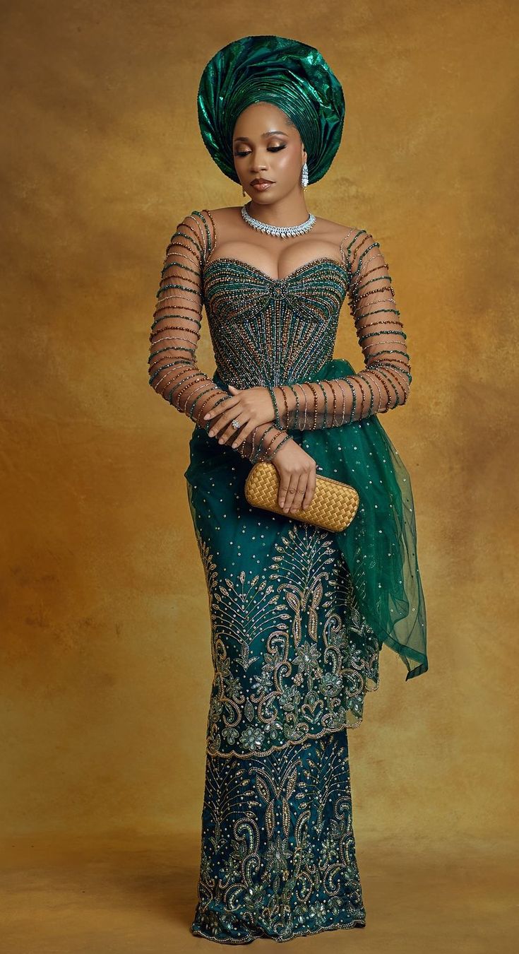 an african woman in a green dress and head scarf holding a gold purse with her right hand