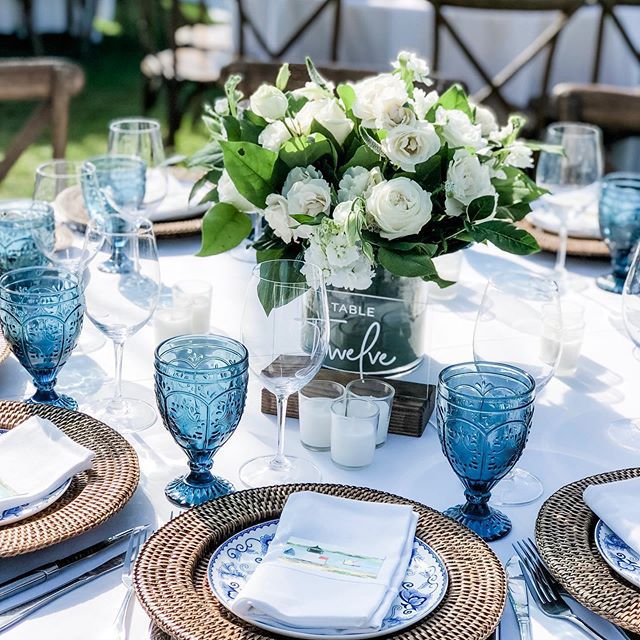 the table is set with blue and white plates, silverware, and vases