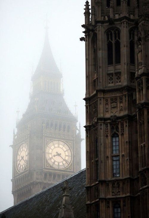 the big ben clock tower towering over the city of london on a foggy day