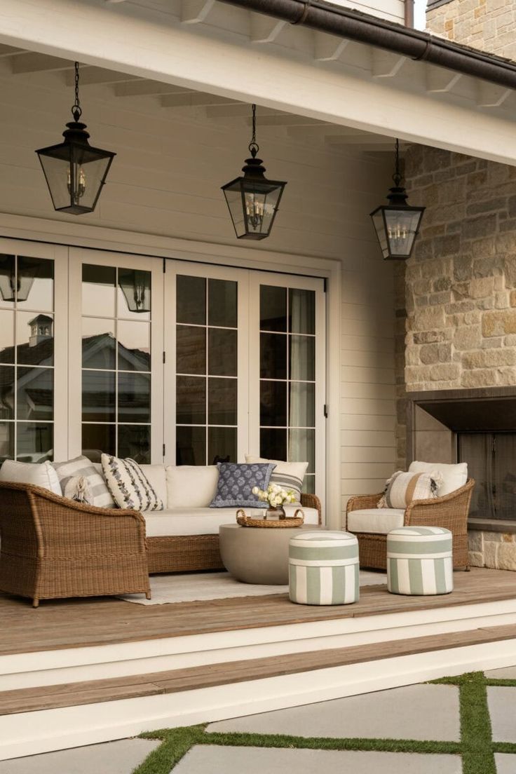 an outdoor living area with wicker furniture and lanterns on the ceiling, along with grass