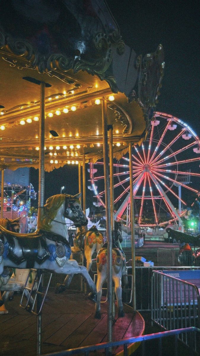 an amusement park at night with carousels and ferris wheel