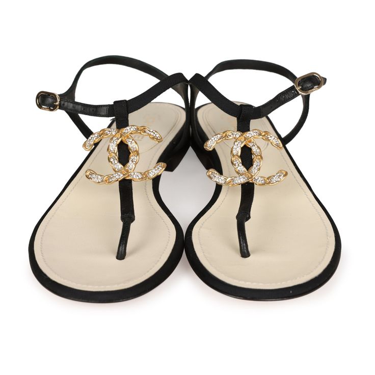 These Chanel Jeweled CC Thong Sandals are in Black Canvas with Gold Hardware. This sandal features a Gold Jeweled CC on the front of the sandal, an adjustable strap, natural leather insole, and rubber sole. Origin: ItalyCondition: New and never wornAccompanied by: Chanel box, dustbagsSize: 37 EU Elegant Beach Slingback Sandals With Leather Sole, Luxury Adjustable Sandals For Summer, Luxury Adjustable Summer Sandals, Designer Single Toe Strap Sandals For Summer, Designer Sandals With Single Toe Strap For Summer, Luxury Black Slingback Sandals With Single Toe Strap, Designer Slingback Sandals With Single Toe Strap For Summer, Luxury T-strap Sandals For Summer, Luxury T-strap Sandals For Beach