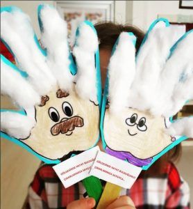 a child holding up two hand puppets made to look like people's hands with fake hair and mustaches on them