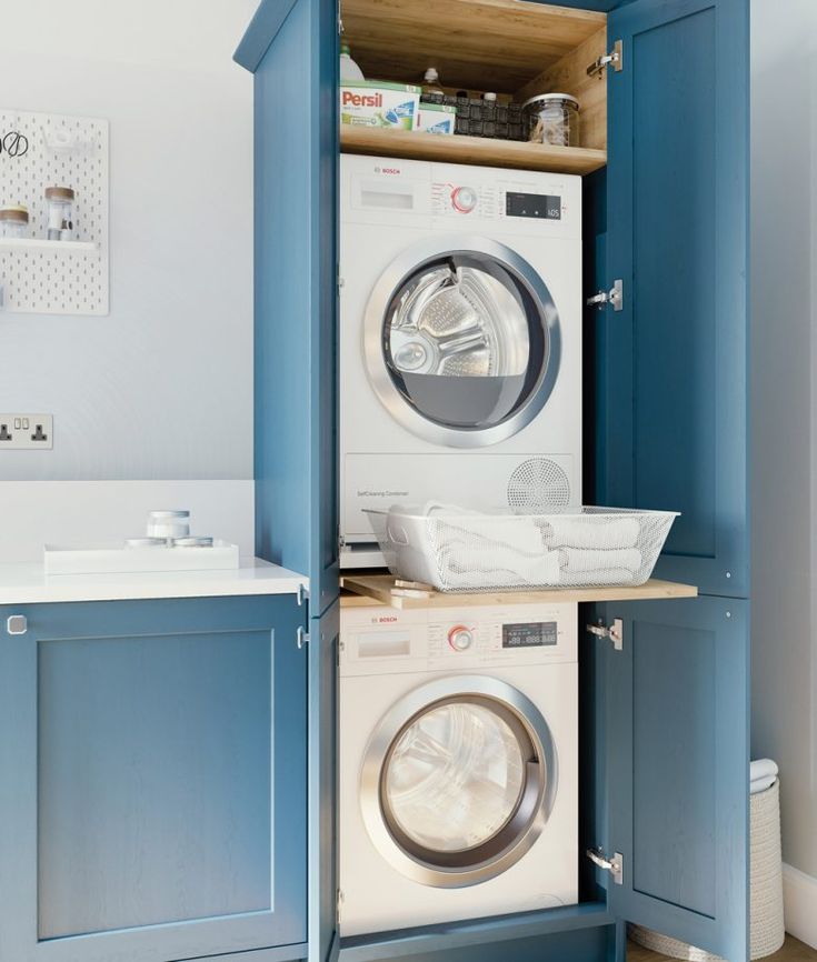 a washer and dryer in a room with blue cupboards on the wall