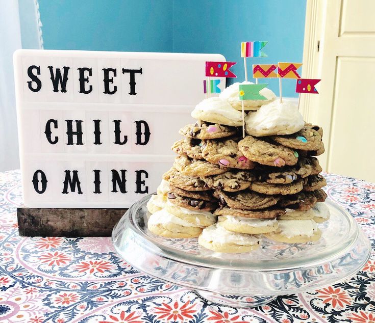 a stack of cookies sitting on top of a glass platter next to a sign that says sweet child omme