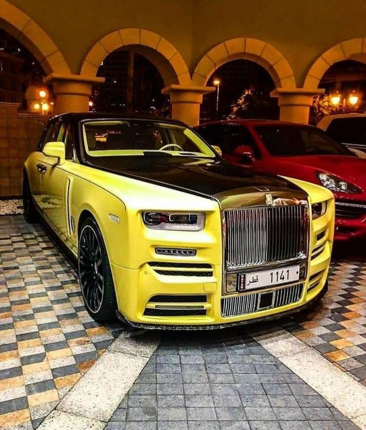 two rolls royces parked next to each other on a checkered floor