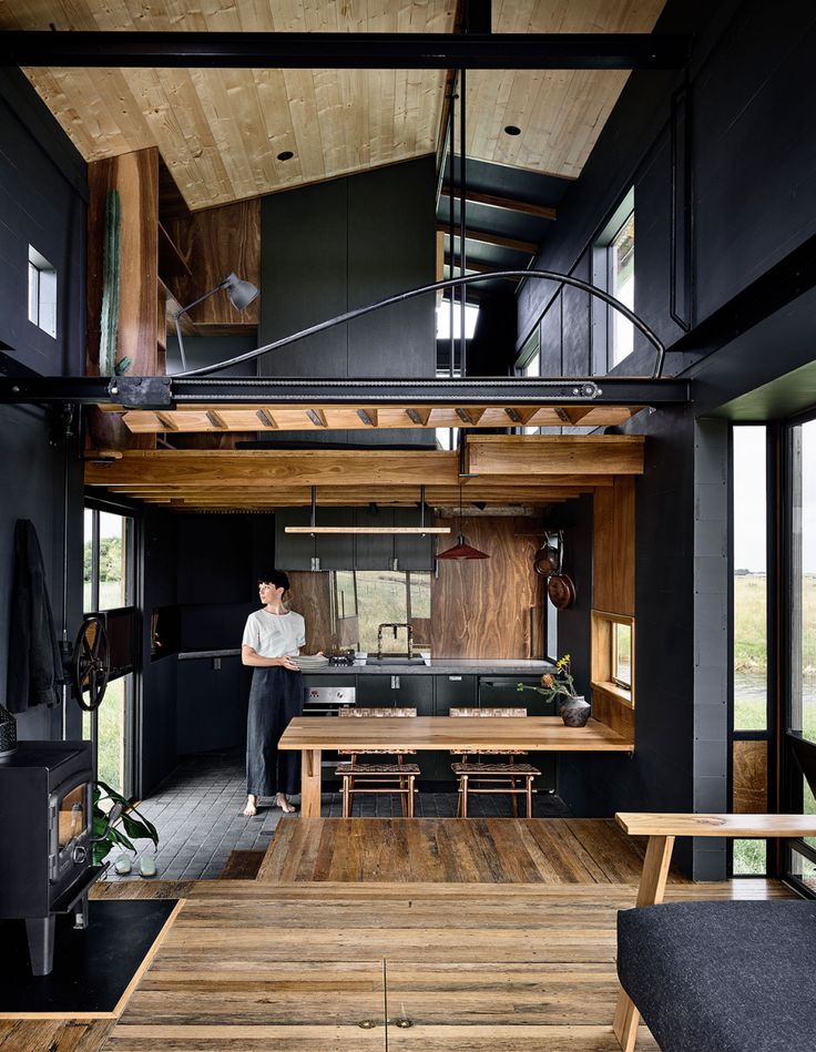 a person sitting at a wooden table in a room with black walls and wood floors