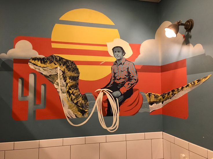 a bathroom with a mural of a man riding a large snake