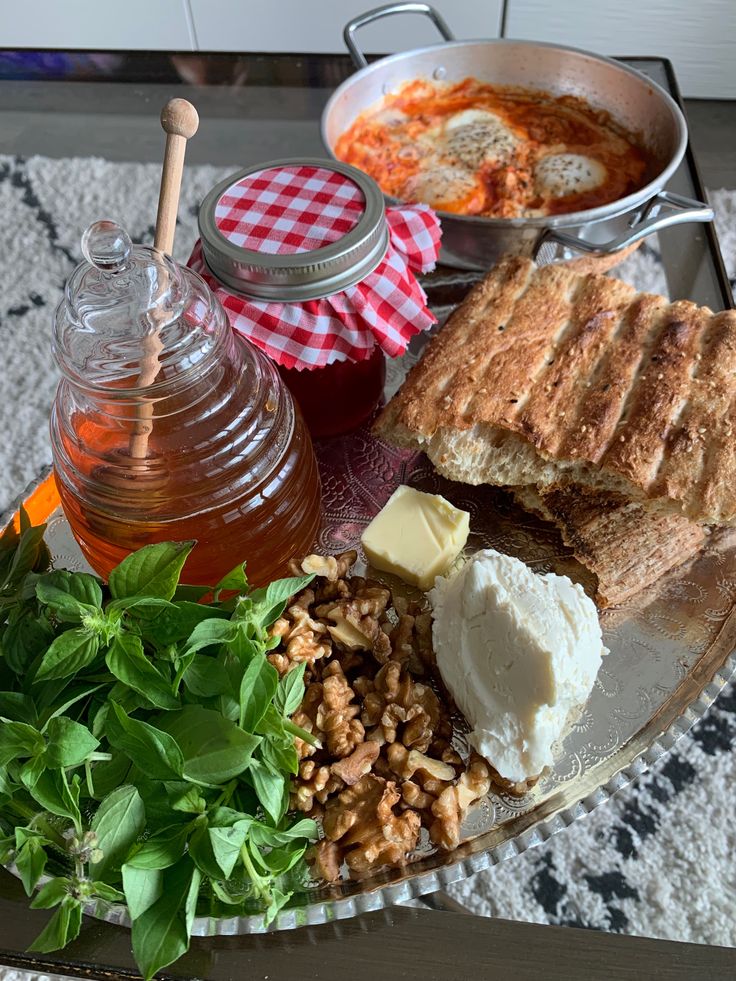 an assortment of food on a plate with water and honey in the bowl next to it