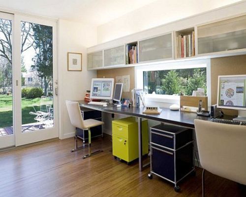 a home office with two desks and chairs in front of a sliding glass door