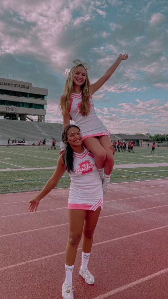 two girls are standing on one another in the middle of a track with their arms around each other