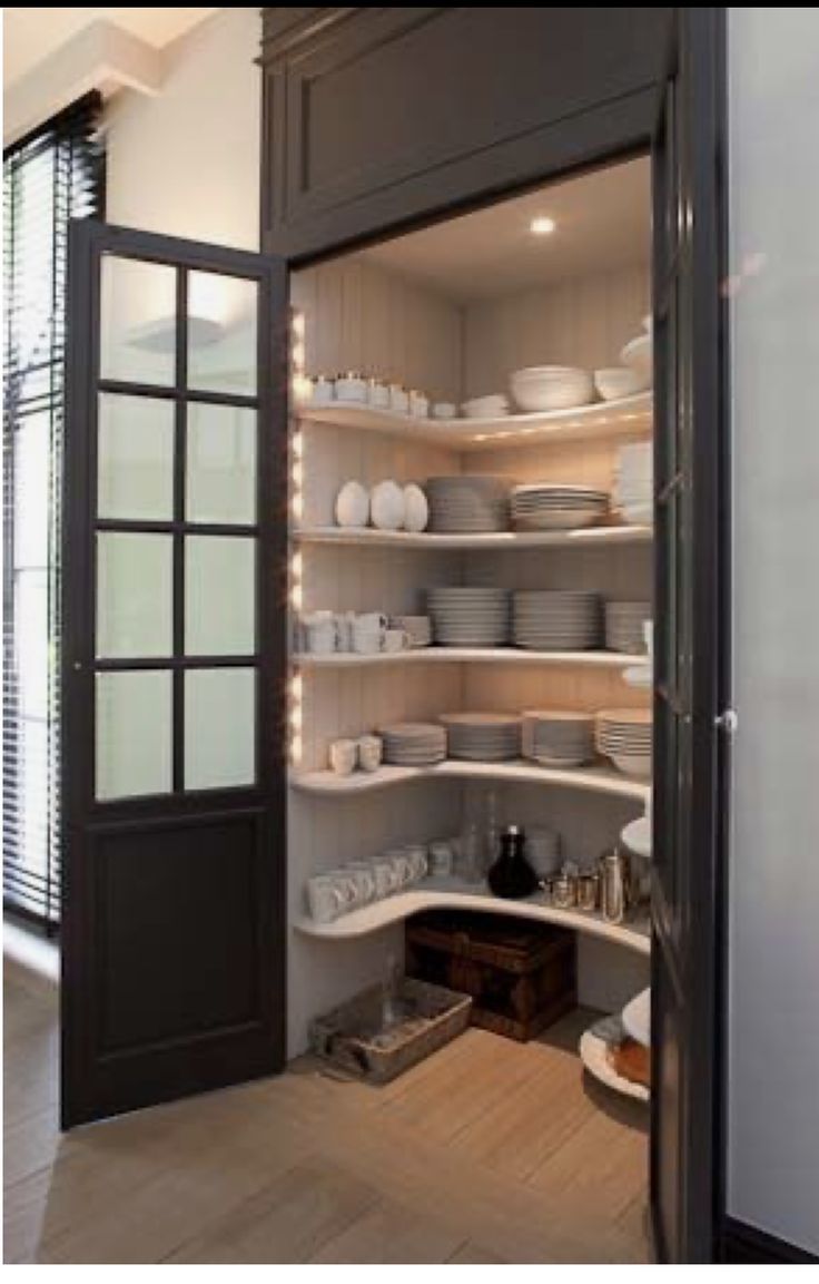 an open pantry with lots of dishes and plates on the shelves in front of it