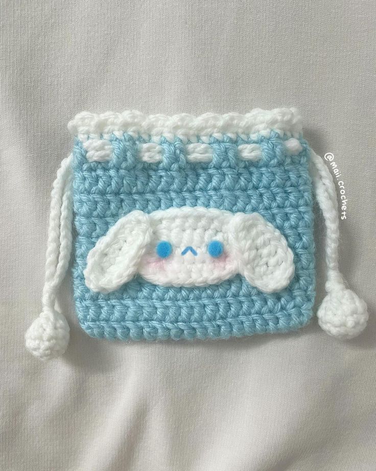 a crocheted blue and white purse with a face on it