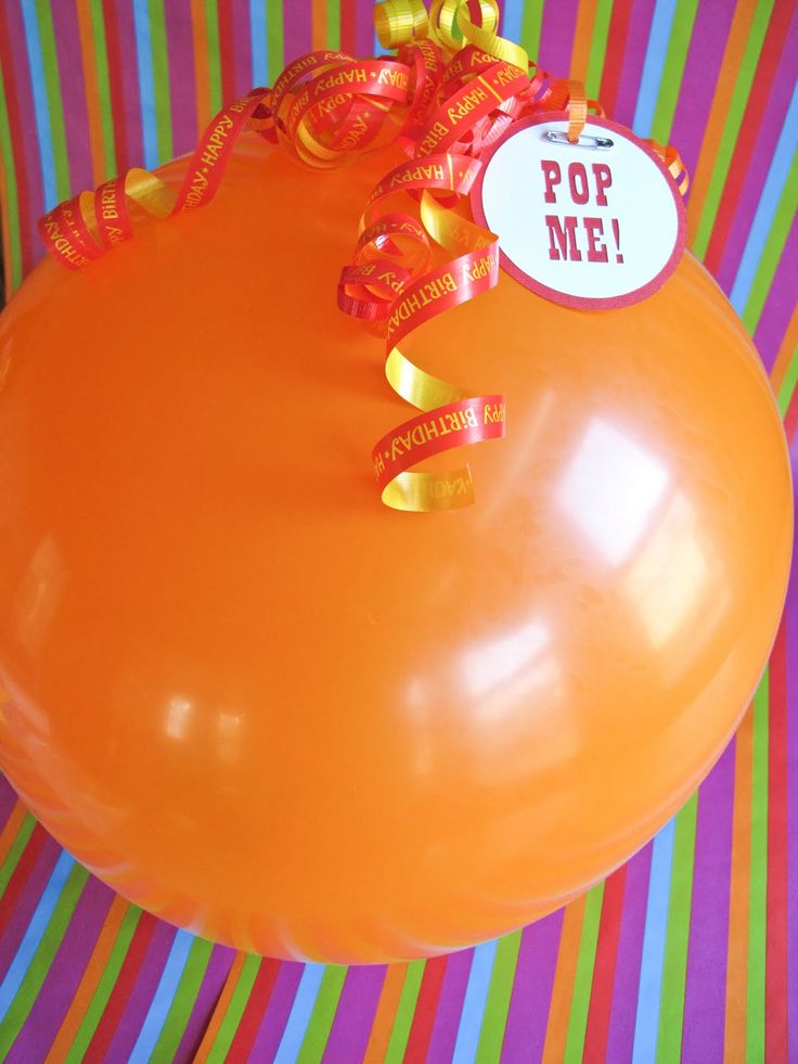 an orange balloon with a ribbon tied around it and a pop me sticker on the top