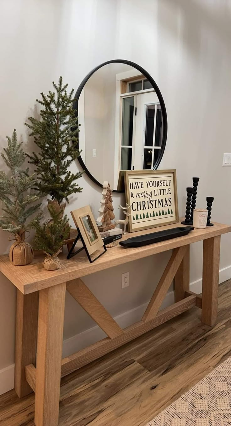 a wooden table topped with a mirror next to a christmas tree and other decor items