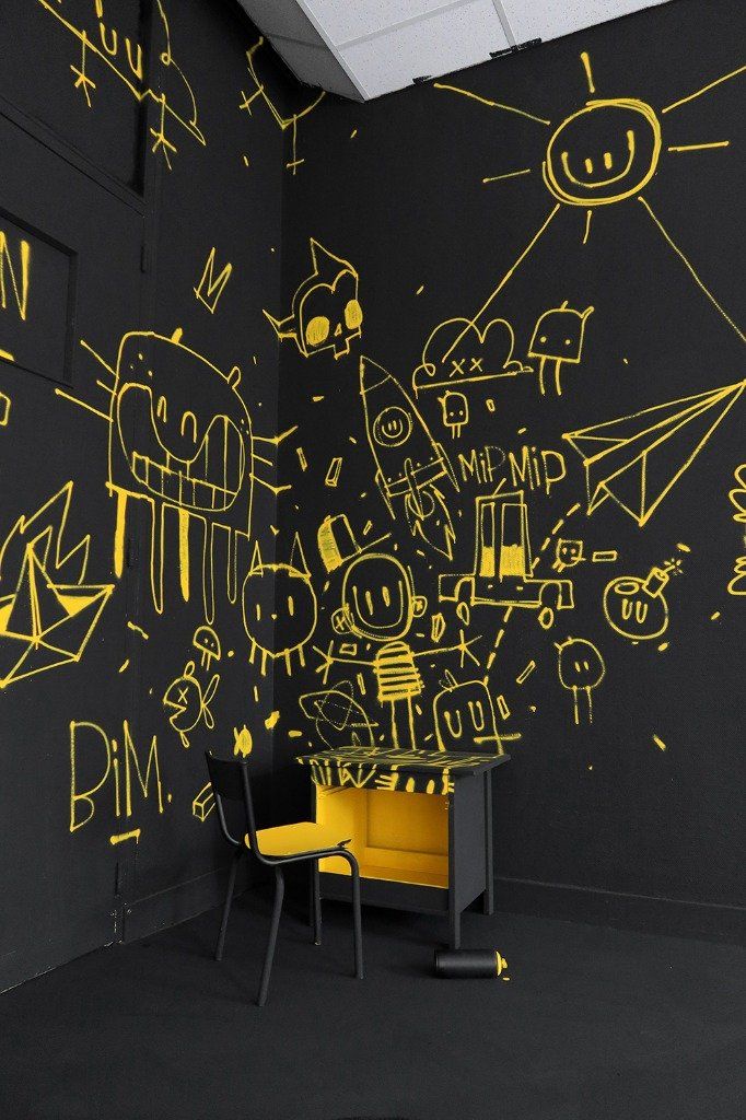 a yellow chair sitting in front of a black wall with graffiti on it's walls