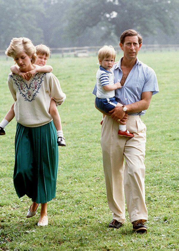 the prince and princess of wales are walking with their young children in a grassy field