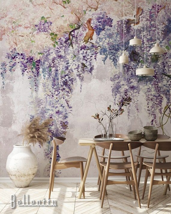 a table and chairs in front of a wall with purple flowers on it, hanging from the ceiling