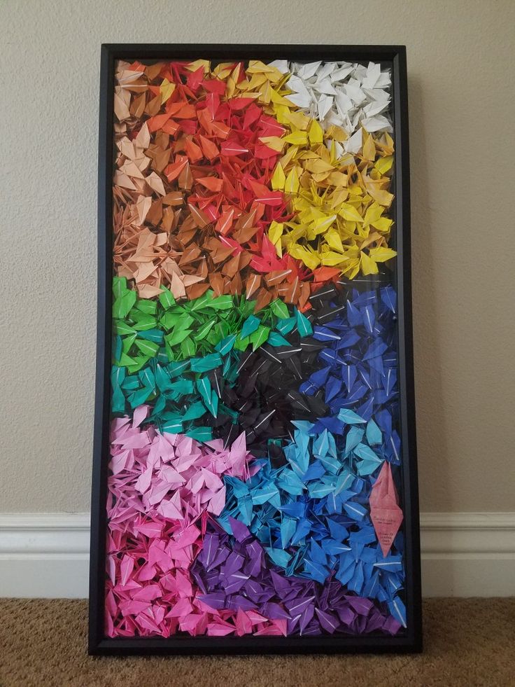 an art piece made out of colored origami paper in a black frame on the floor