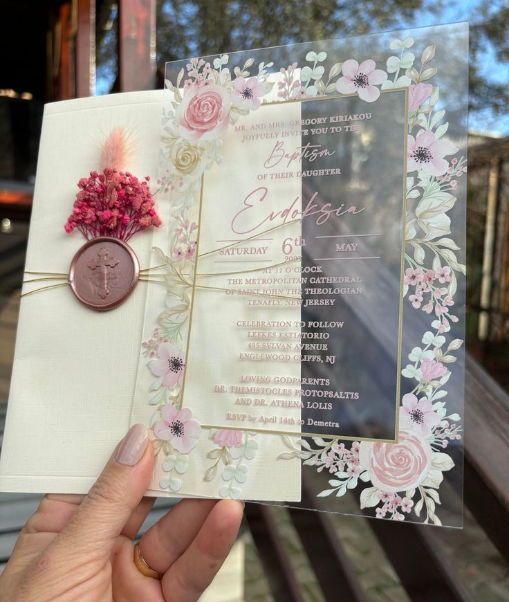 a person holding up a wedding card with flowers on it