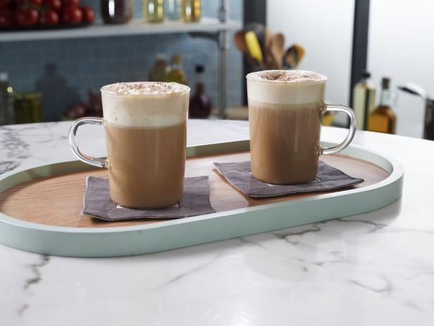 two cups of coffee sitting on top of a wooden tray next to eachother