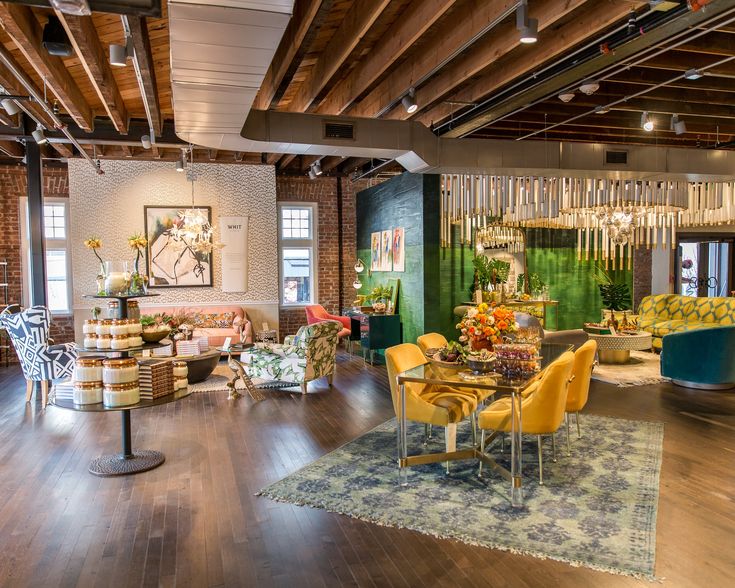 a room with chairs, couches, tables and chandelier hanging from the ceiling