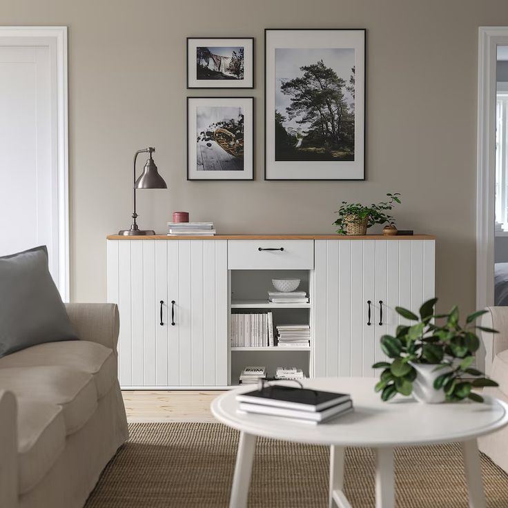 a living room with white furniture and pictures on the wall above it's entertainment center