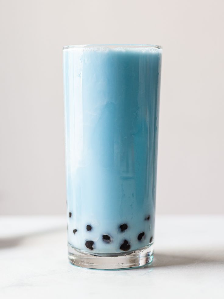 a glass filled with blue liquid sitting on top of a table