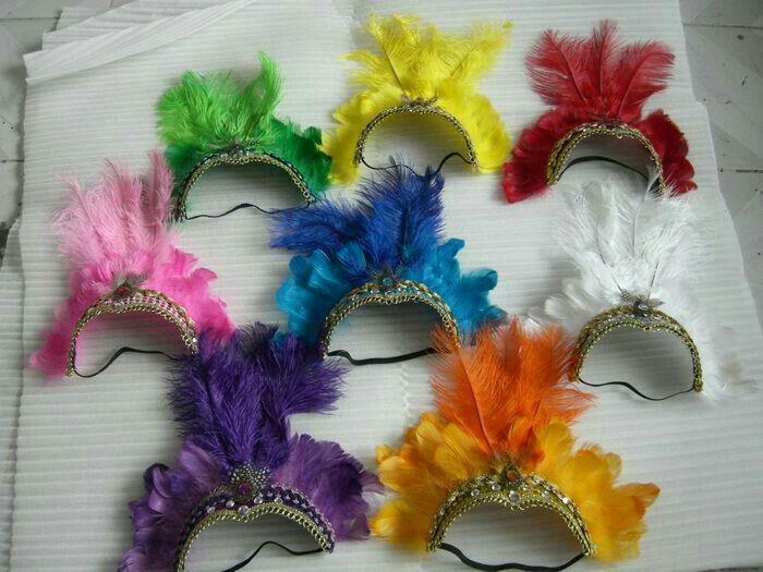 six different colored feathered masks on top of a white sheet