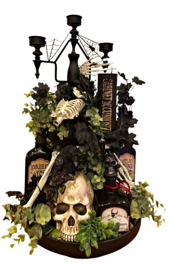 a halloween decoration with skulls, candles and plants