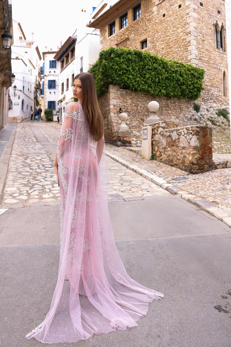 a woman in a pink dress is standing on the street with her back to the camera