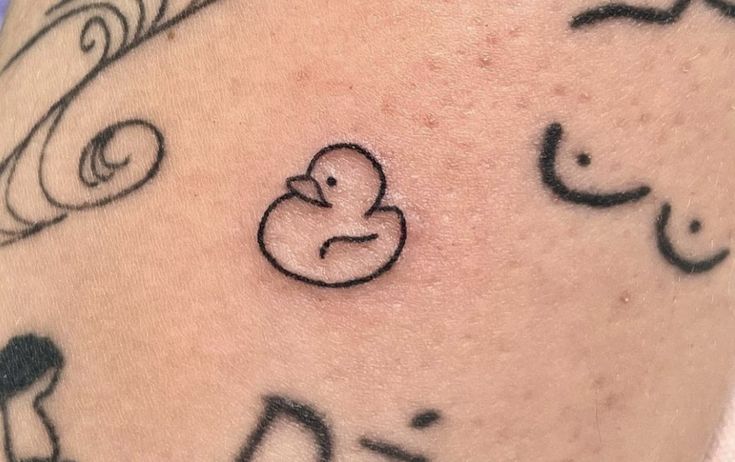 a close up of a person's arm with tattoos on it and an image of a rubber duck