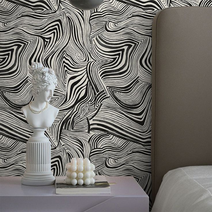 a white vase sitting on top of a table next to a wallpapered wall