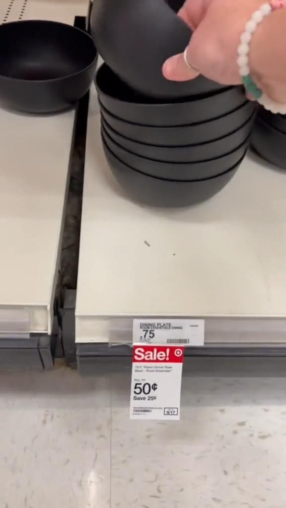 a person reaching for a black bowl on top of a scale in a store display