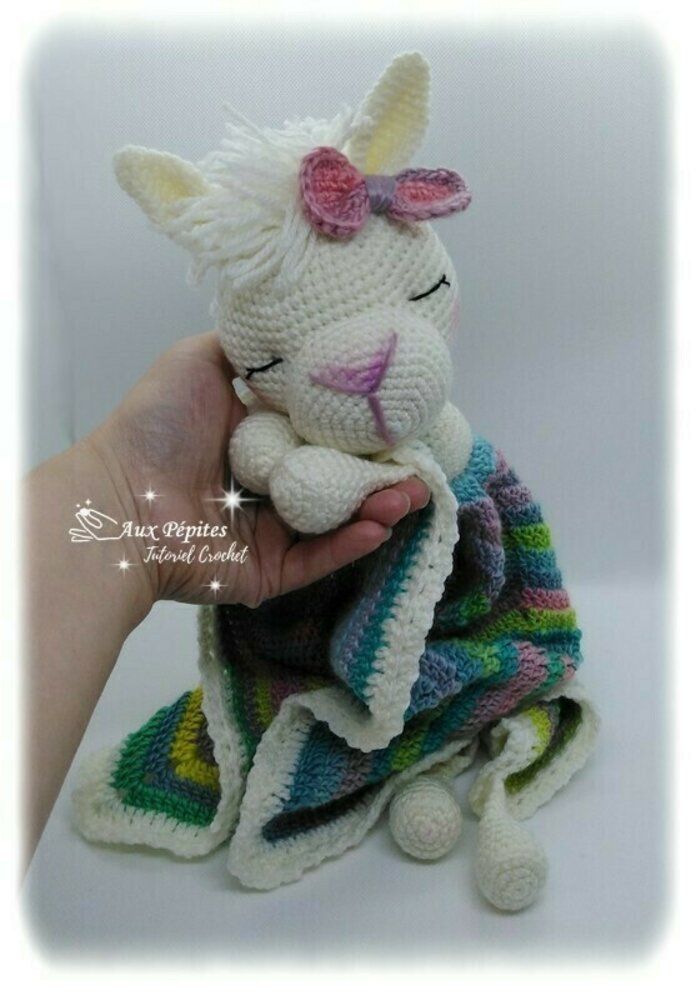 a crocheted stuffed animal with a blanket around it's neck is being held by a hand