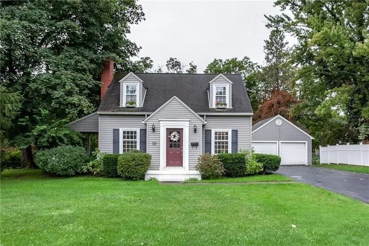 a gray house with white shutters and red door