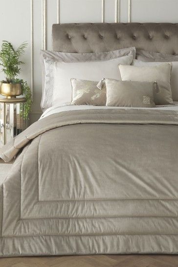 a bed with white linens and pillows in a small room next to a plant