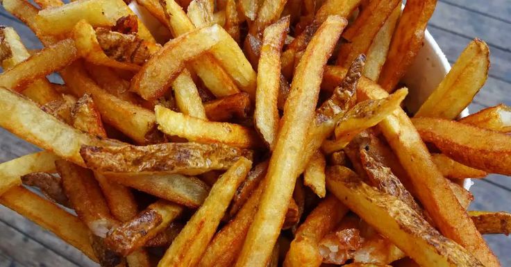 french fries in a white bowl on a wooden table