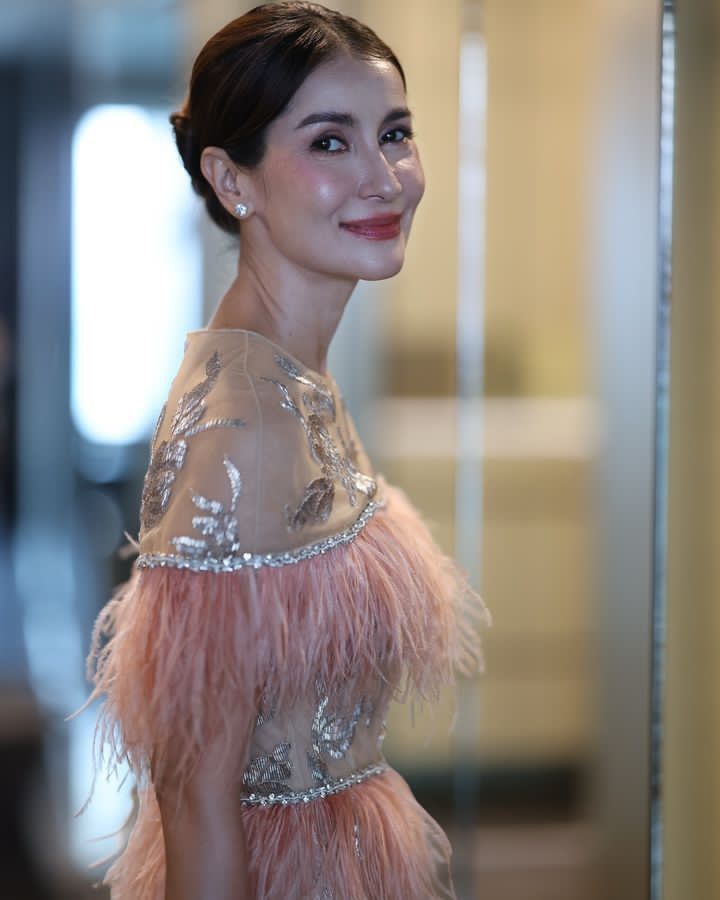 a woman in a pink feathered dress smiling at the camera