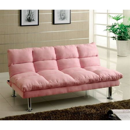 a pink futon sofa sitting on top of a white floor next to a potted plant