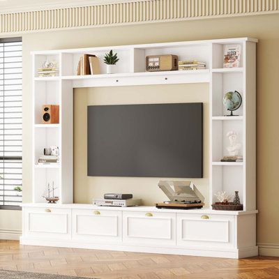 a white entertainment center with bookshelves and a flat screen tv mounted on the wall