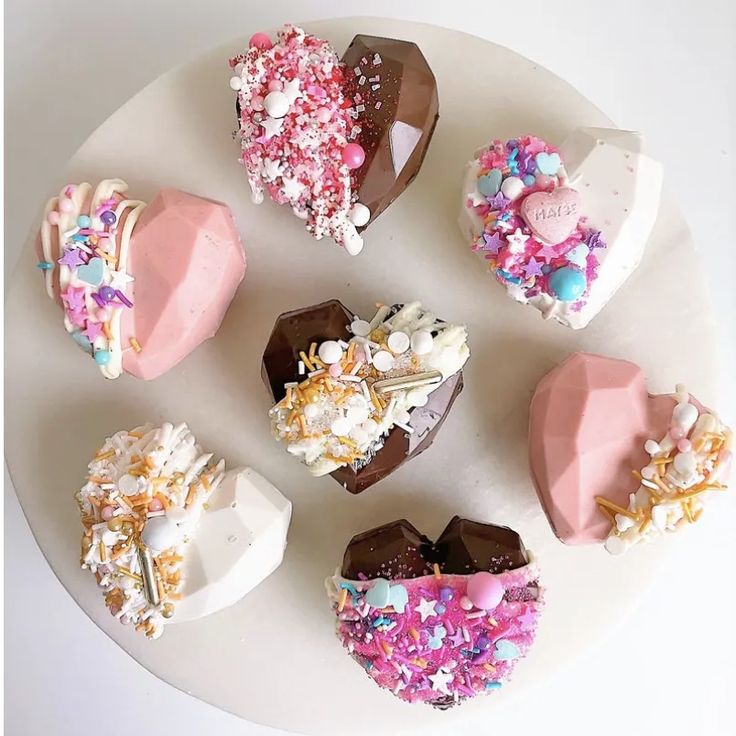 there are many heart shaped desserts on the white plate with confetti and sprinkles