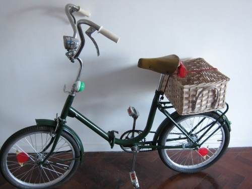 a bike with a basket on the front and handlebars is parked against a wall