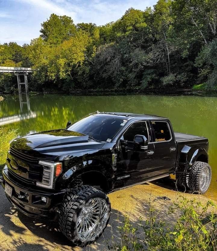 a black truck parked next to a lake