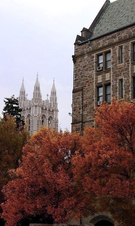 an old building is surrounded by trees with orange leaves