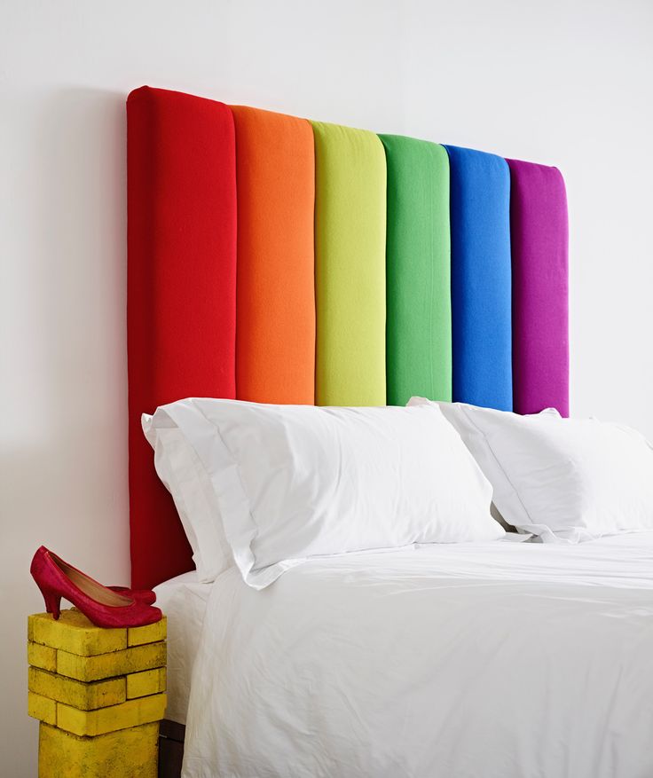 a rainbow colored headboard with white sheets and pillows